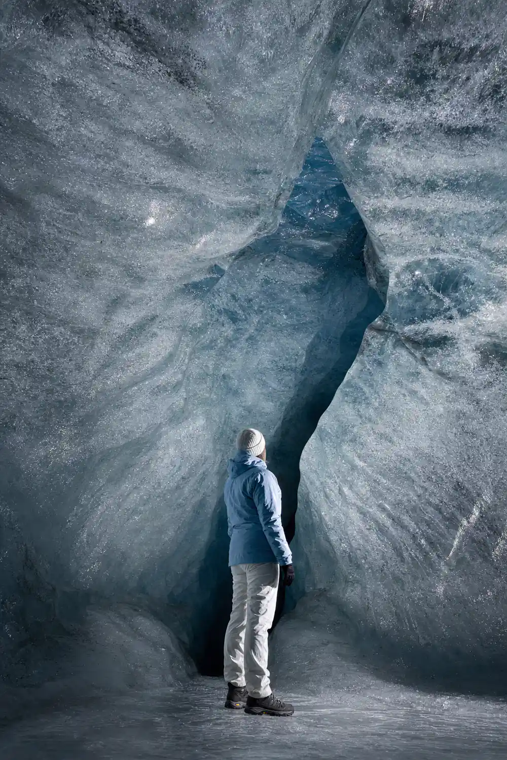 Aerial view of glacier crevasse with dark rocky terrain