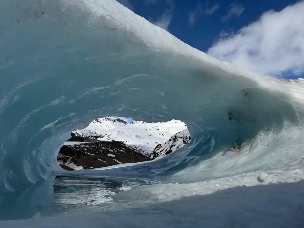 Blue ice cave entrance with swirling patterns and dark opening