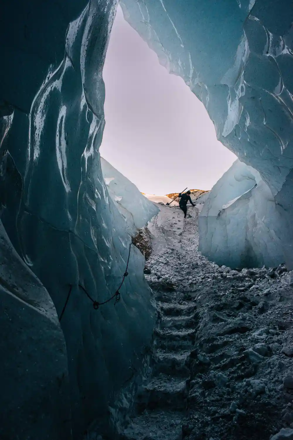 Climber ascending icy crevasse with rope equipment
