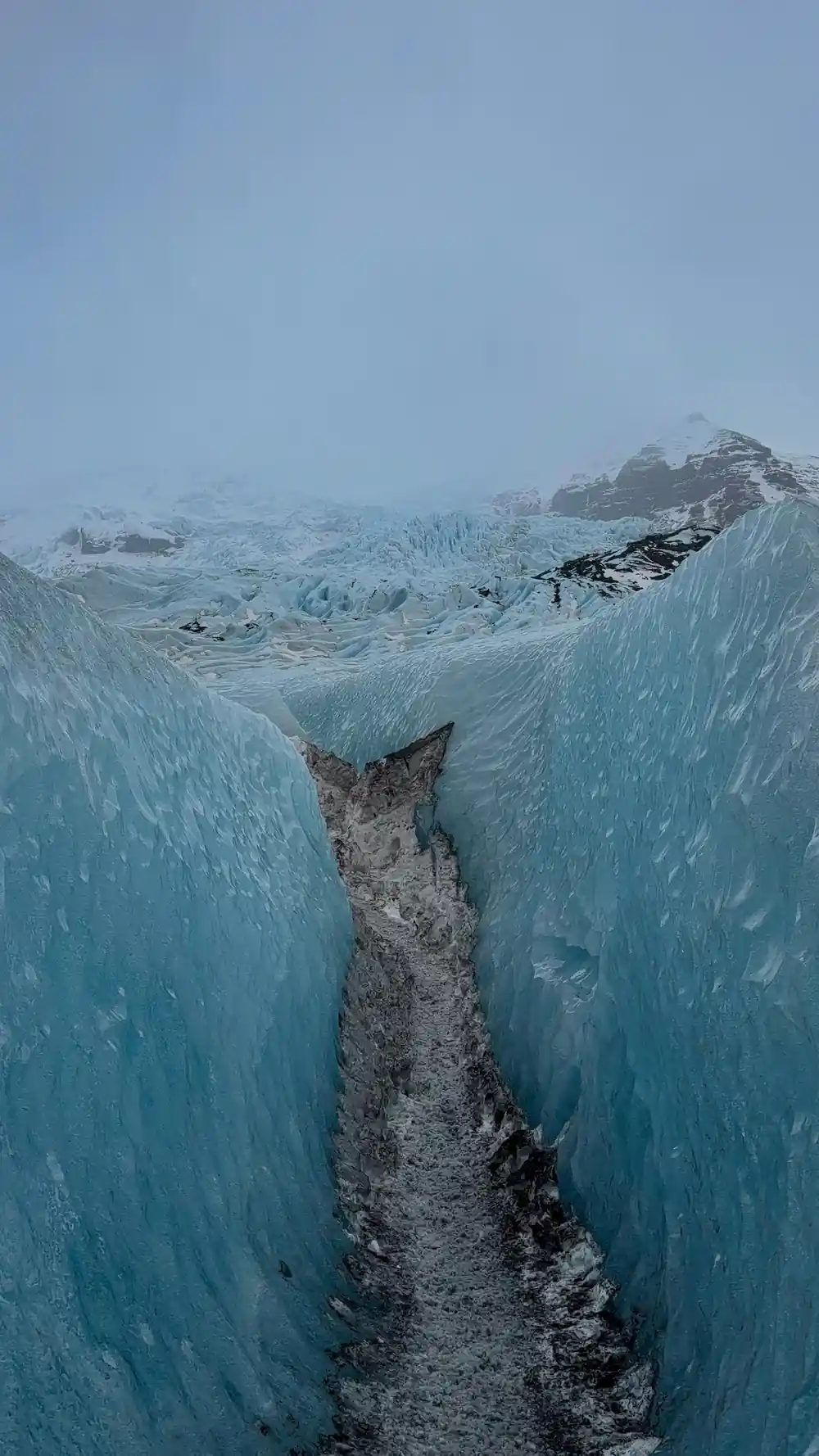 Crevasse cutting through blue glacier ice from above