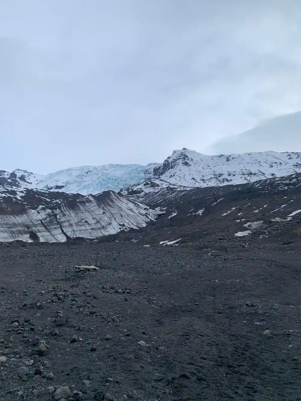 Dark volcanic landscape with distant snow-covered mountain