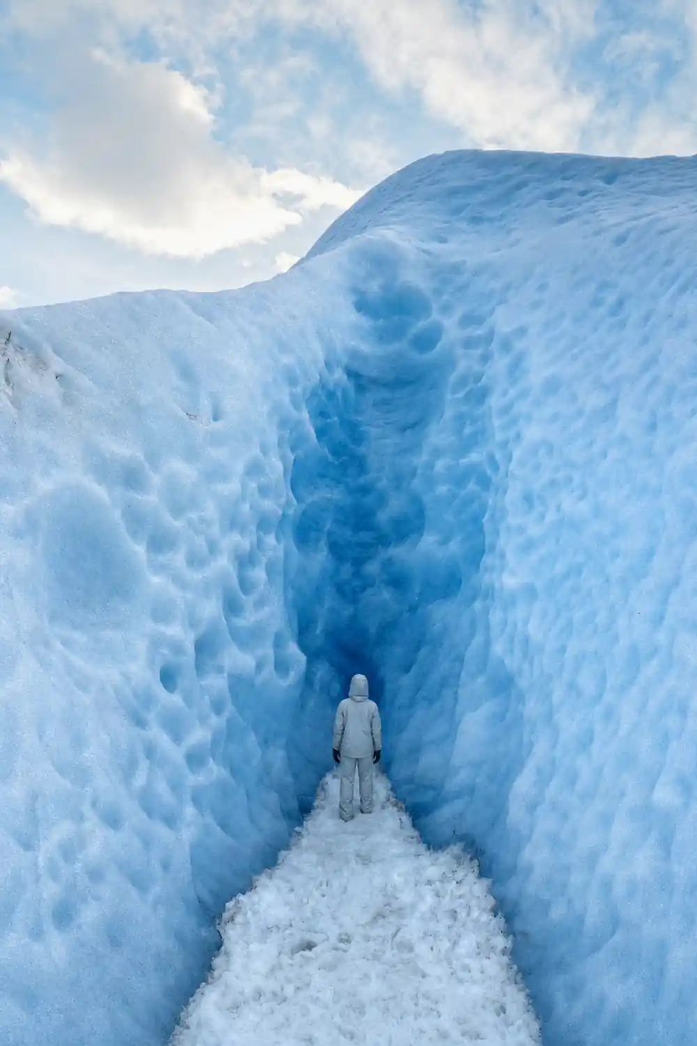 Deep narrow crevasse in glacier ice viewed from above