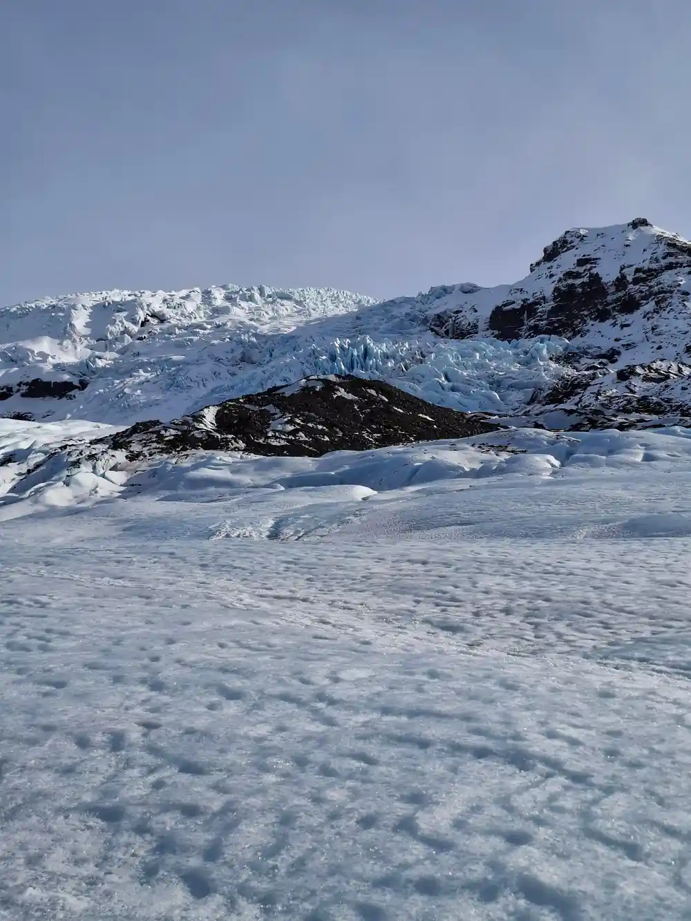 Glacier flowing between mountains with snow field