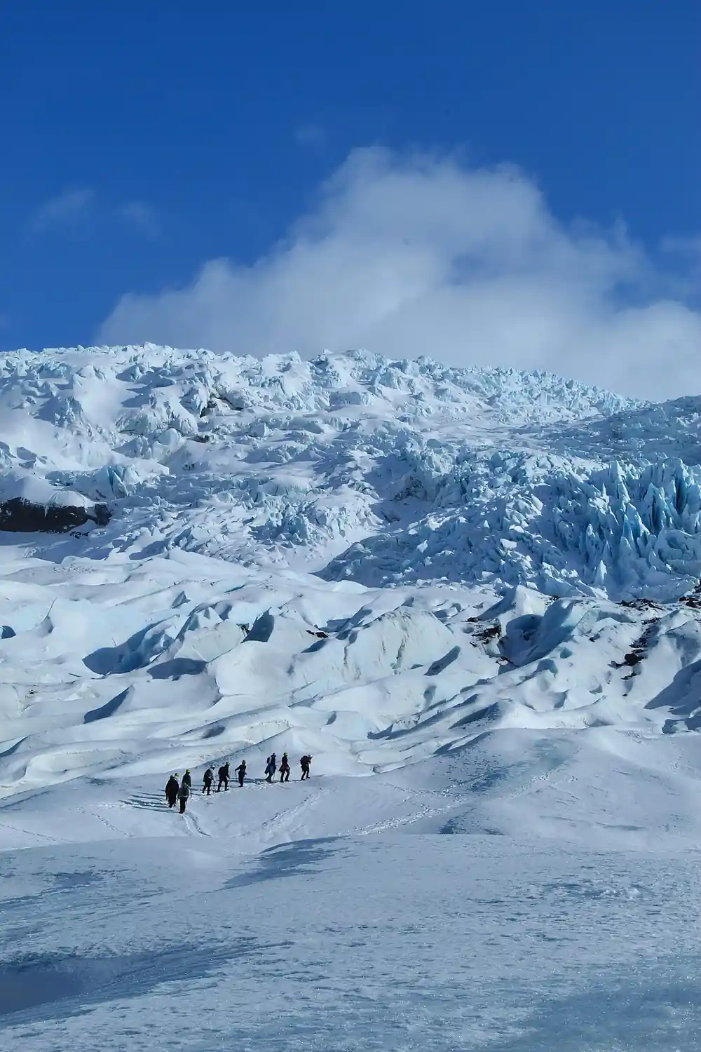 Group of hikers on snowy glacier with mountains