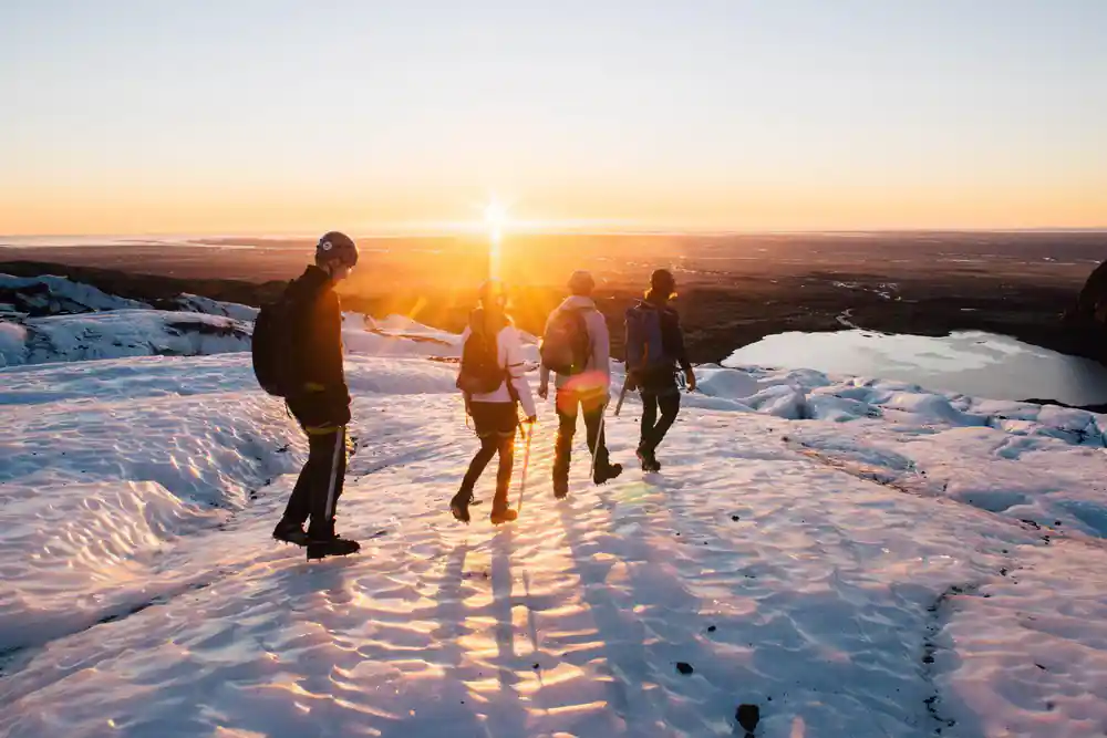 Group hiking on snowy slope at golden hour sunset