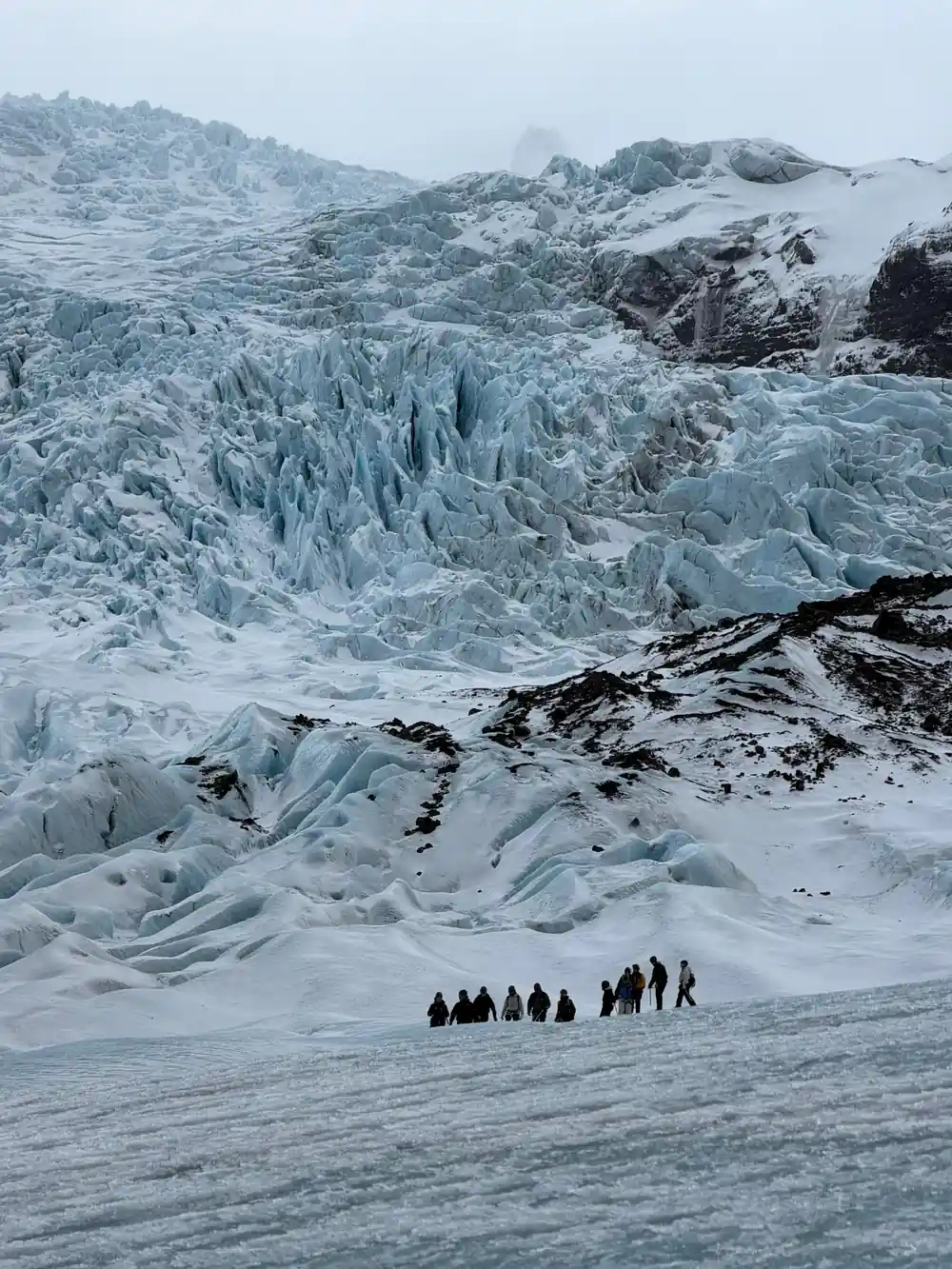 Group of tourists walking on glacier with crevasses
