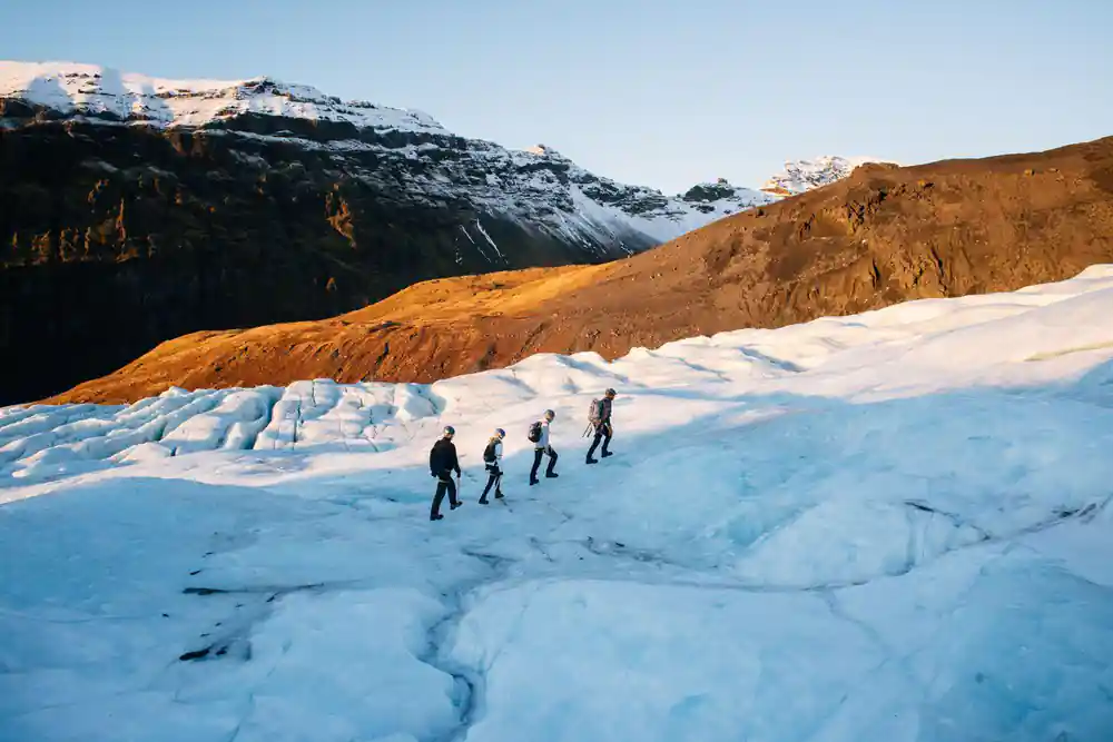 Group walking on glacier with snowy mountains behind