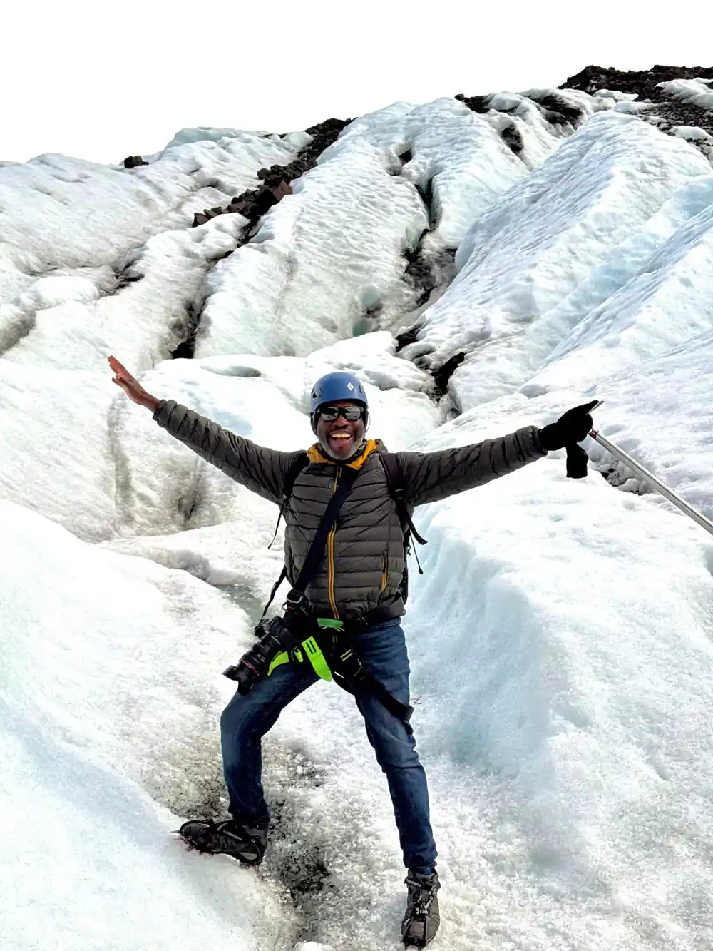 Hiker with arms raised standing on white glacier ice