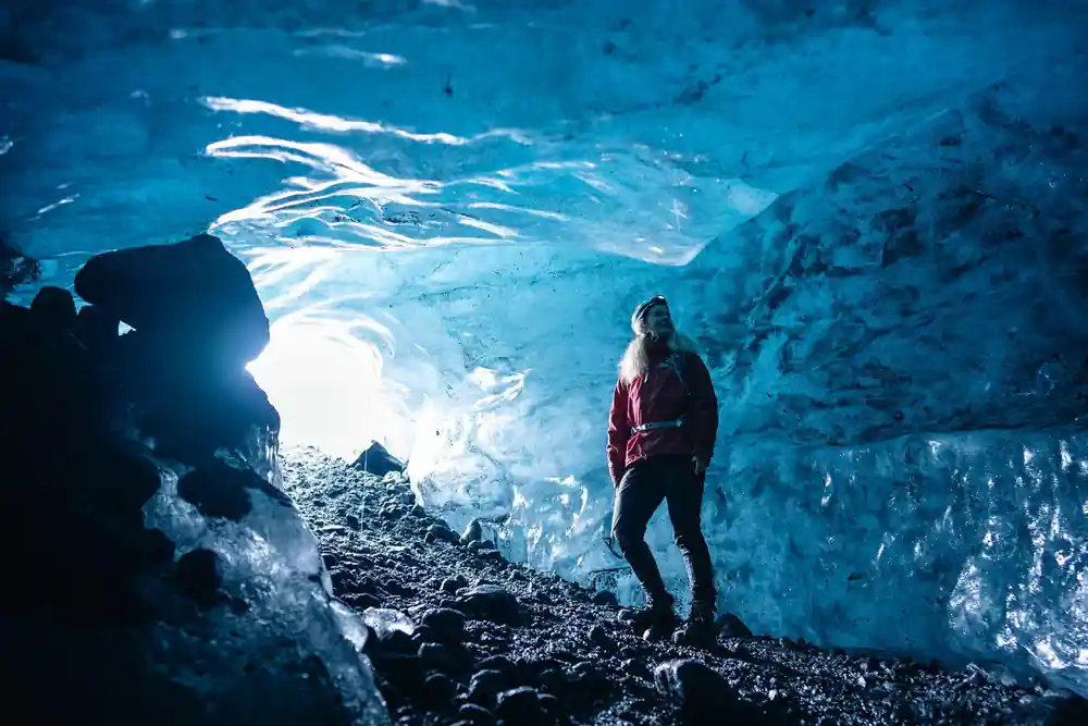 Hiker in red jacket inside luminous ice cavern