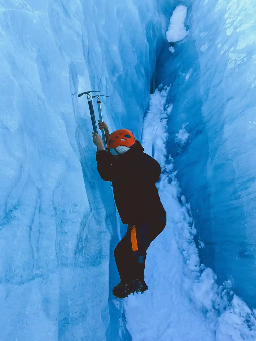 Ice climber with ice axe on vertical frozen surface