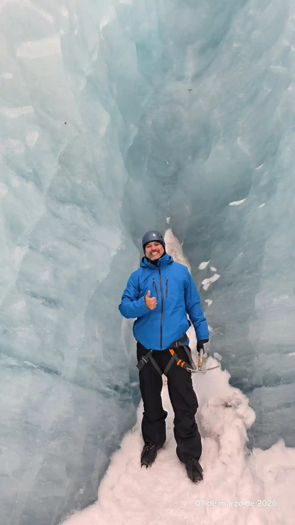 Man standing in narrow blue ice crevasse