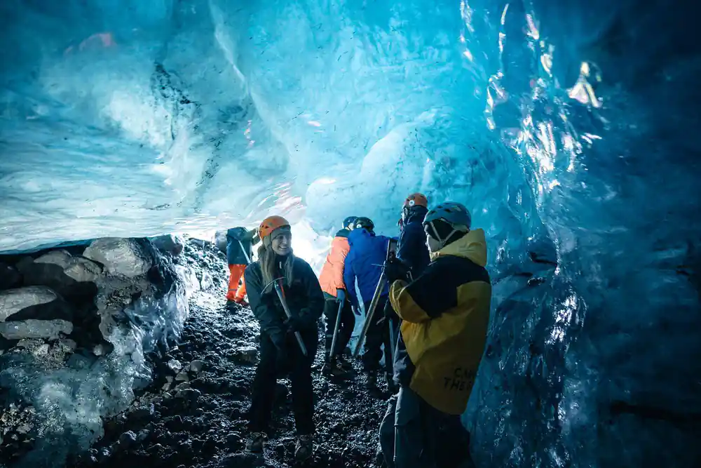 Multiple people inside bright blue ice cave interior