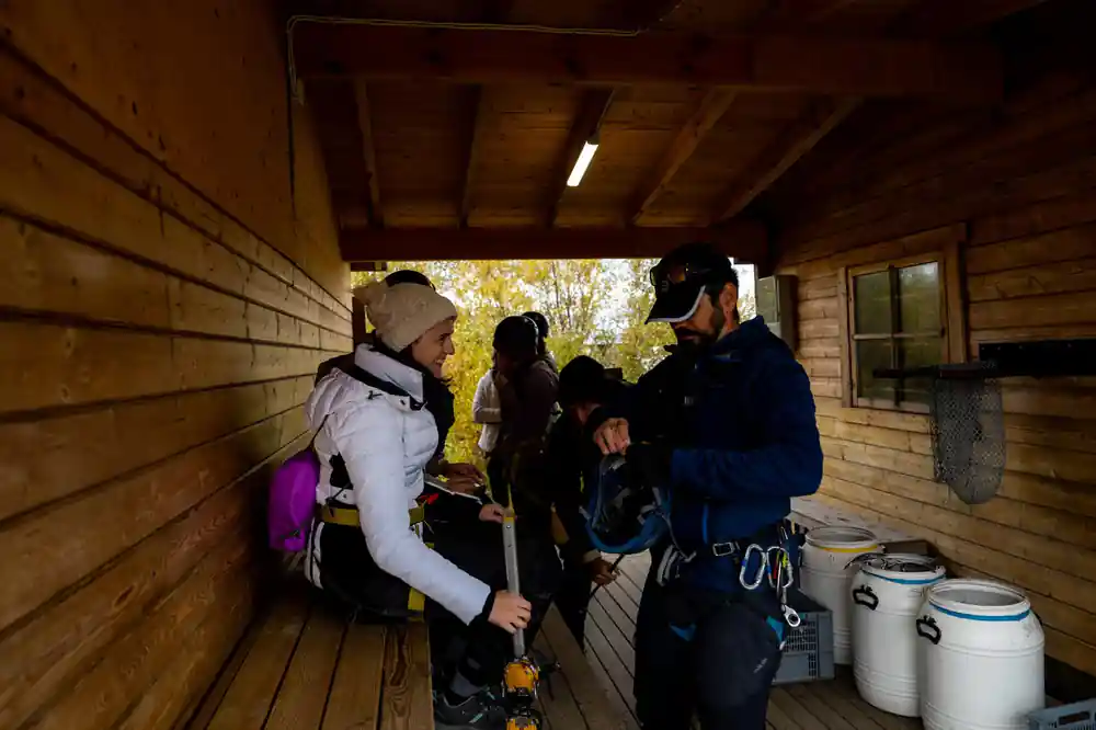 People preparing equipment inside wooden shelter