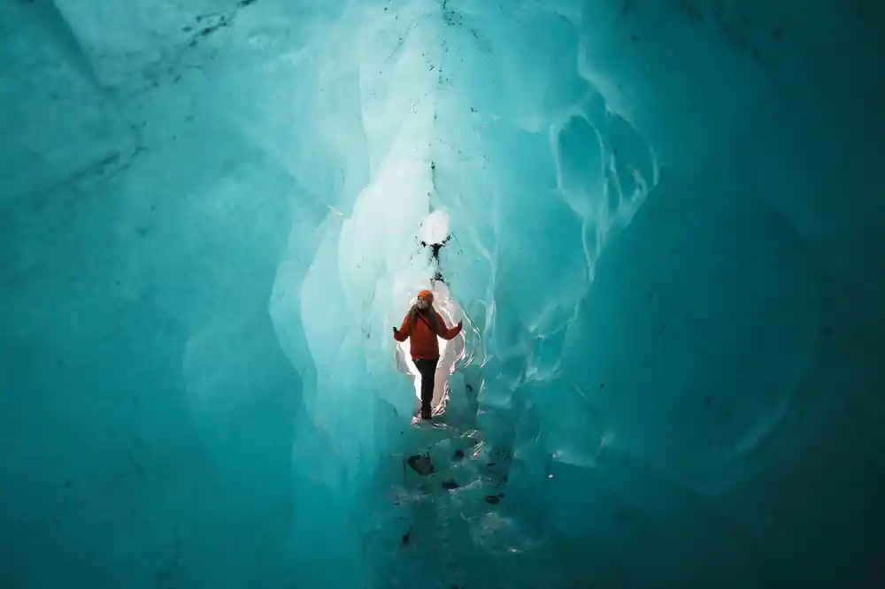 Person ascending narrow passage between ice walls