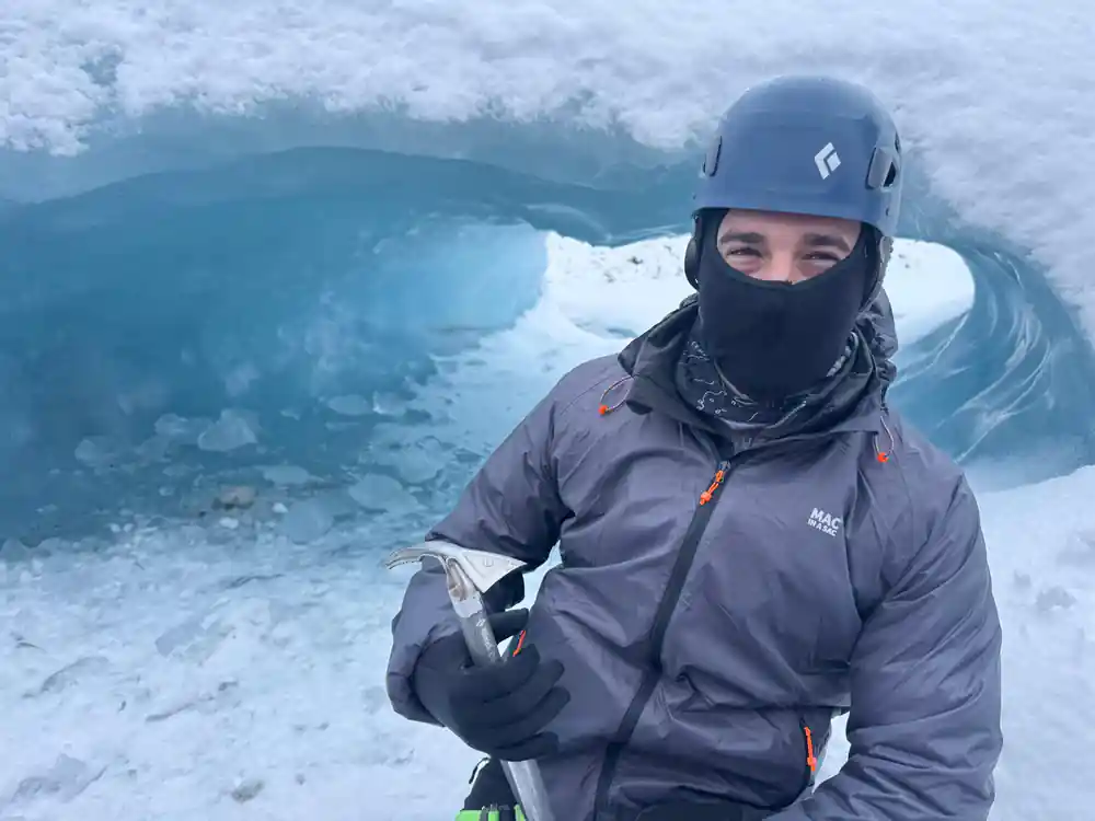 Person in climbing helmet at blue ice cave opening