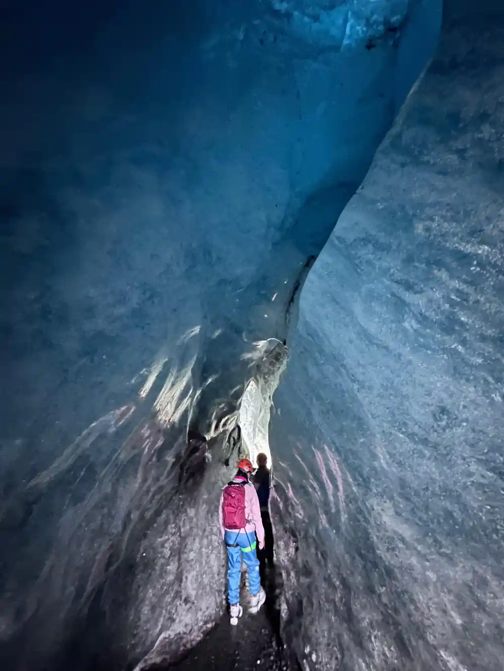 Person walking deep between towering blue glacier walls
