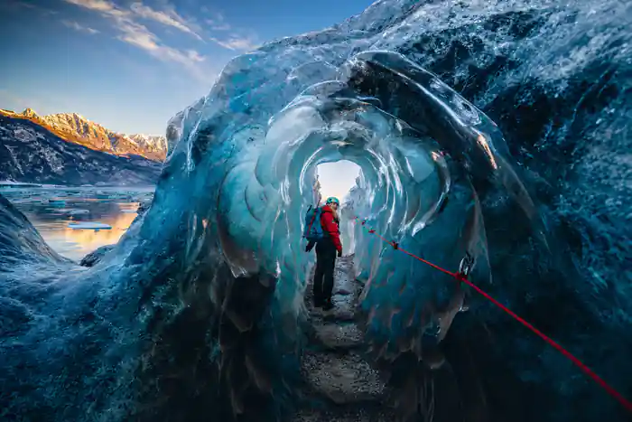 Person walking through blue ice cave tunnel