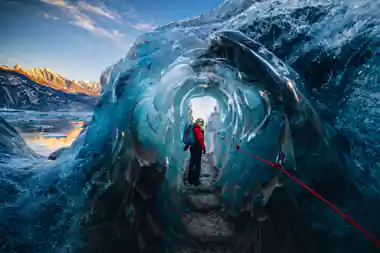 Person walking through blue ice cave tunnel