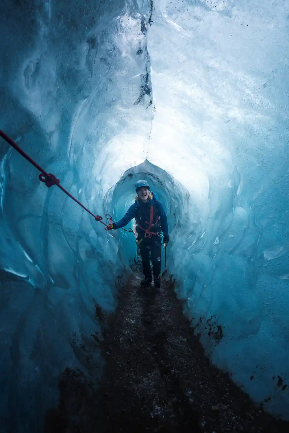Person walking through narrow blue ice crevasse