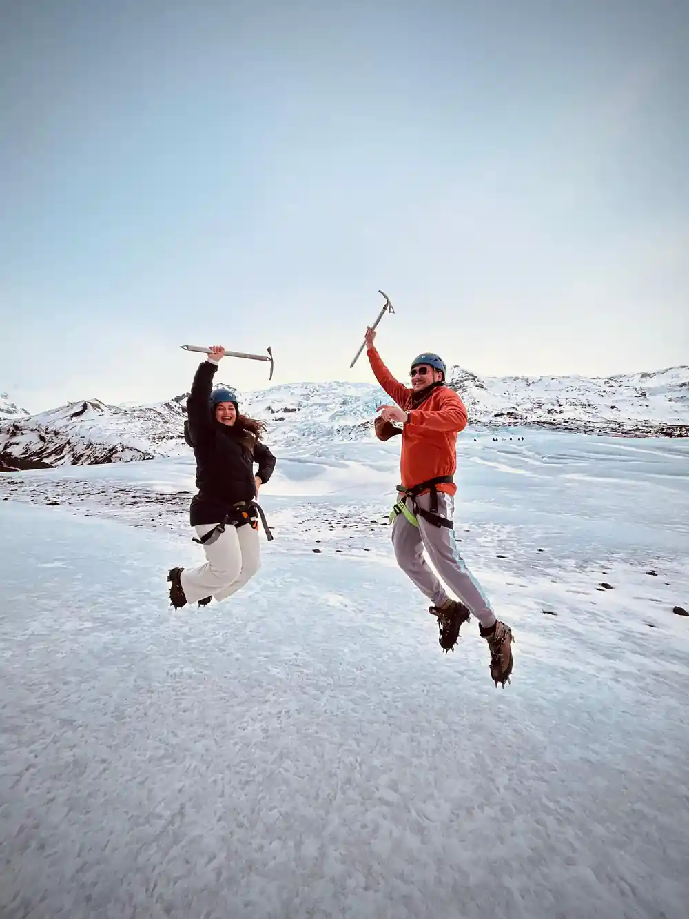 Two people jumping on frozen lake with ice axes