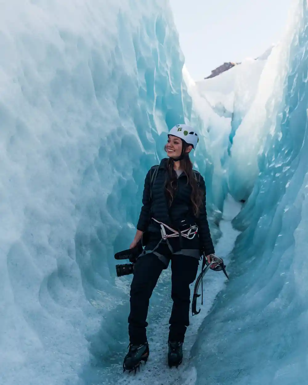 Woman in climbing gear inside ice cave passage