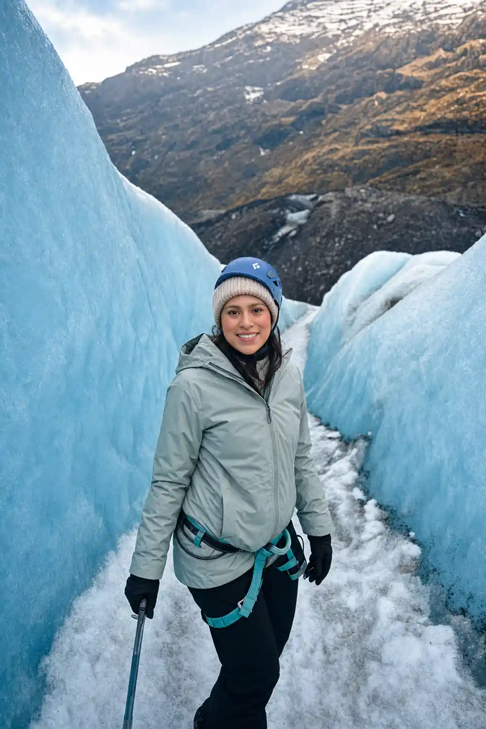 Woman walking between tall blue glacier ice walls